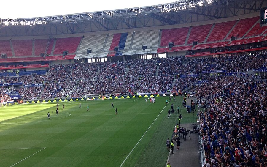 Le Groupama Stadium plein pour un match de l'Olympique Lyonnais, vu depuis les tribunes hautes avec le terrain et la foule en contrebas