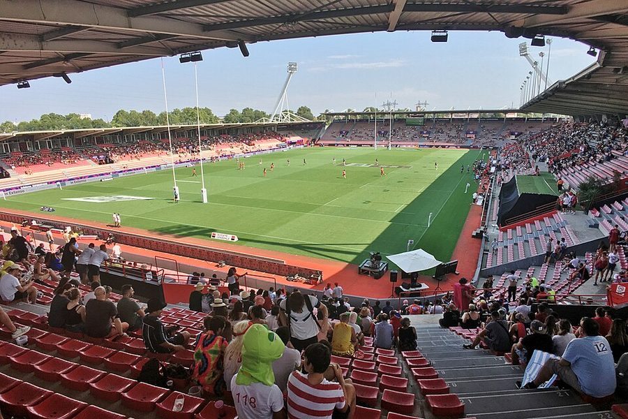Le stade Ernest-Wallon à Toulouse rempli de public lors d'un tournoi de rugby à VII, vue depuis les tribunes hautes avec le terrain en contrebas