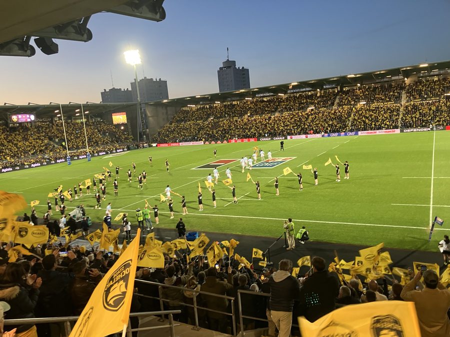 Le stade Marcel-Deflandre de La Rochelle plein en soirée de match de Top 14, tribunes jaune et noir et joueurs entrant sur la pelouse