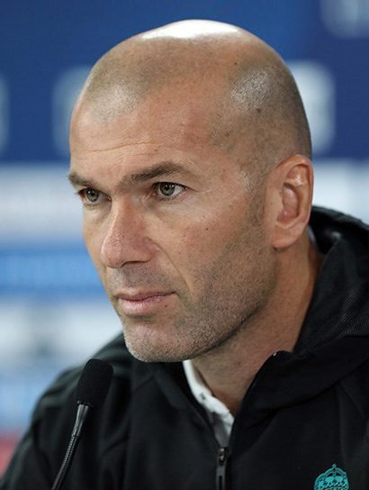 Zinédine Zidane en conférence de presse, costume sombre, micro à la main