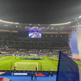 Supporters agitant des drapeaux tricolores devant des fumigènes avant un match de l'équipe de France