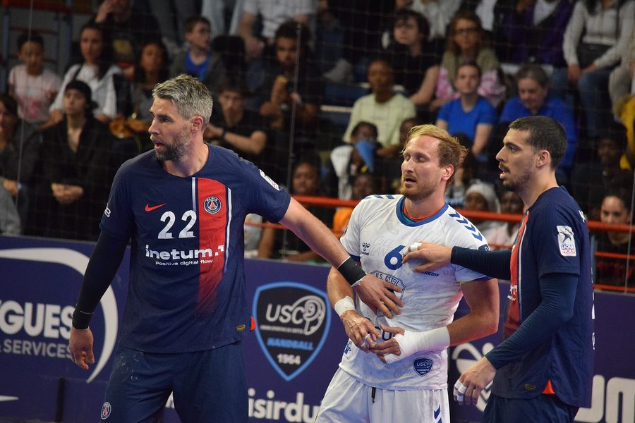 Des joueurs du Paris Saint-Germain et de l'US Créteil au contact devant le public pendant un match du championnat de France de handball