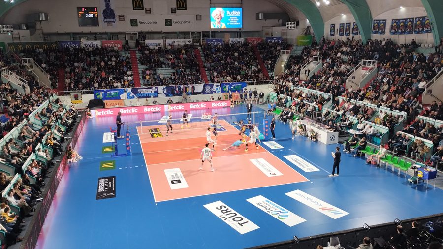 Vue plongeante sur le terrain de la salle Robert-Grenon de Tours pendant un match de volley entre Tours et Tourcoing, les tribunes garnies tout autour du parquet