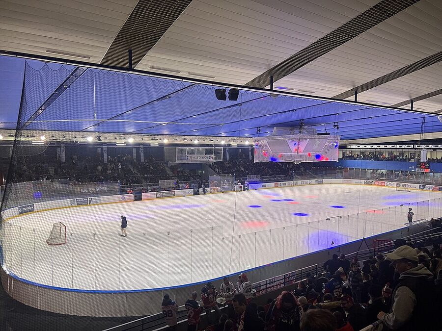 L'intérieur de la patinoire Charlemagne à Lyon, la glace éclairée et les tribunes garnies de spectateurs un soir de hockey